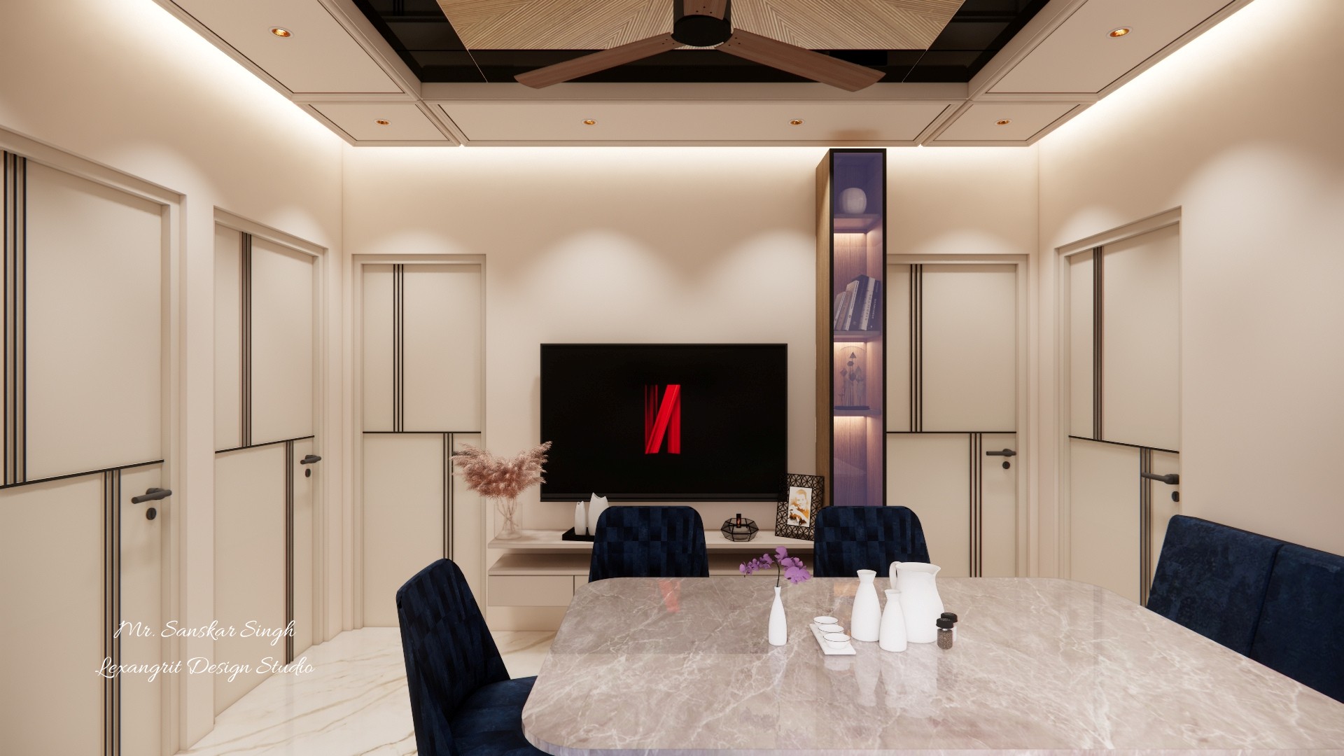 Dining area with a pale marble table and navy chairs facing a television wall, flanked by paneled doors and a lit display niche.