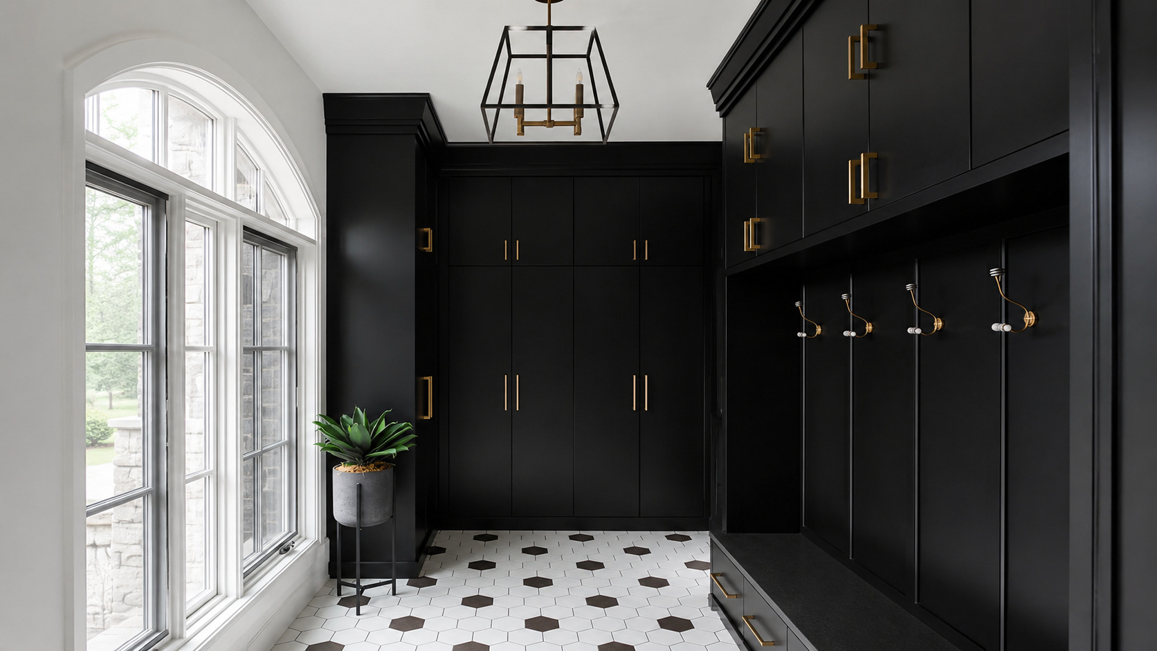 Modern black mudroom with built-in cabinets, brass handles, hexagon tile floor, and stylish entryway storage.
