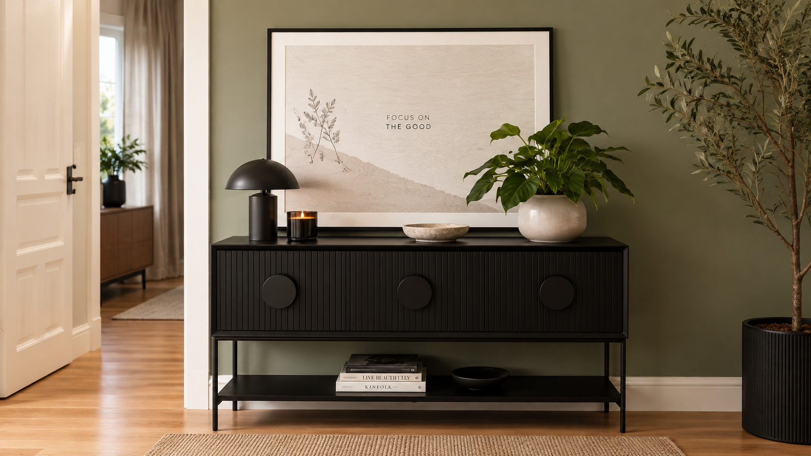 A stylish entry hallway featuring a sleek black console table, oversized framed artwork, decorative accessories, and lush greenery to create a warm and inviting first impression.