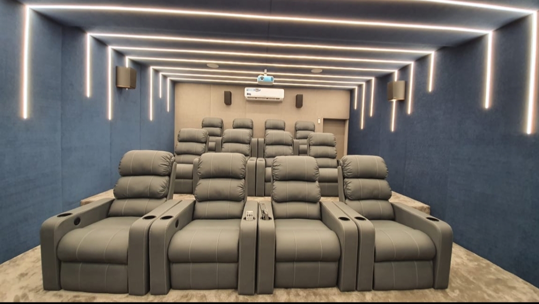 Three tiered rows of fabric home-theatre recliners with cup holders and a carpeted riser step